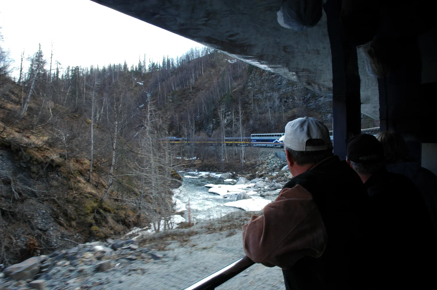 Passenger looking out of a rail tour car at a river canyon